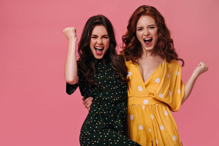 optimistic-women-in-bright-dresses-happily-shout-on-pink-background-joyful-girlfriends-with-curly.jpg
