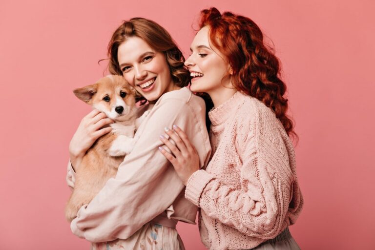 wonderful-girls-holding-cute-dog-isolated-on-pink-background-studio-shot-of-smiling-european-ladie.jpg